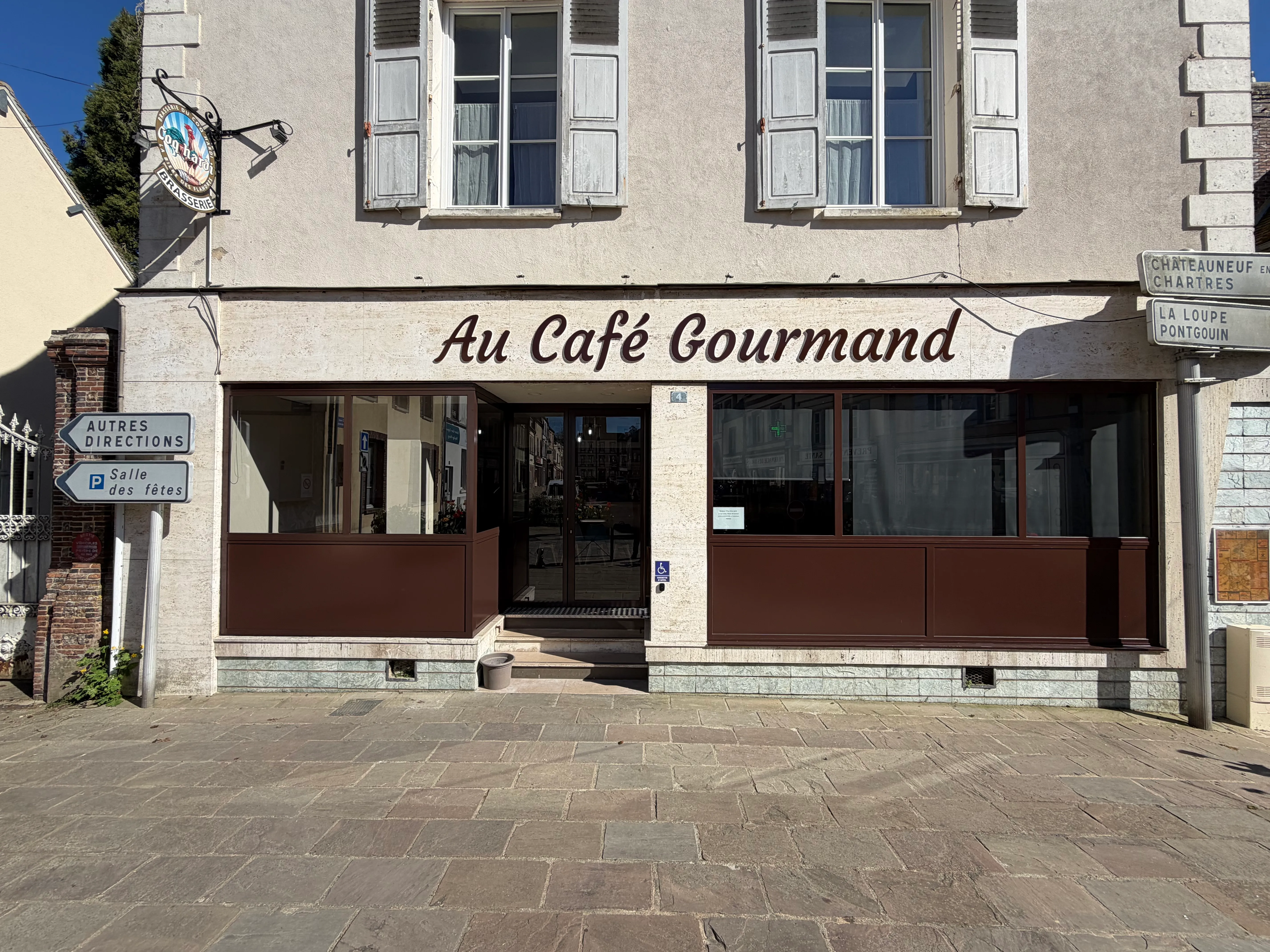 Façade extérieure rénovée d'un commerce affichant une vitrine moderne avec ossature en acier et panneaux inférieurs en tôle d'aluminium assortis au logo.