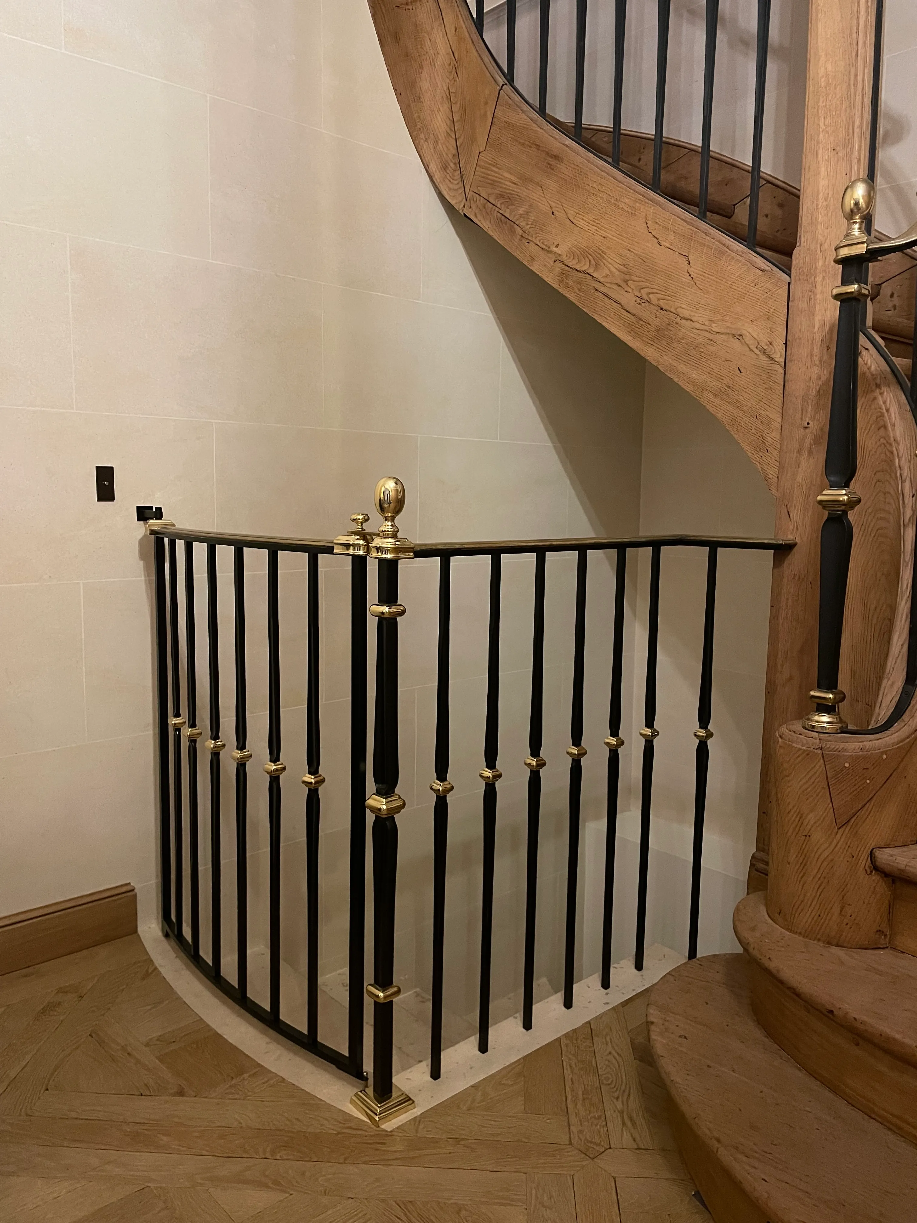 Garde-corps de sécurité en acier laqué noir avec bagues en laiton poli, installé sur un escalier en bois ancien à Paris.
